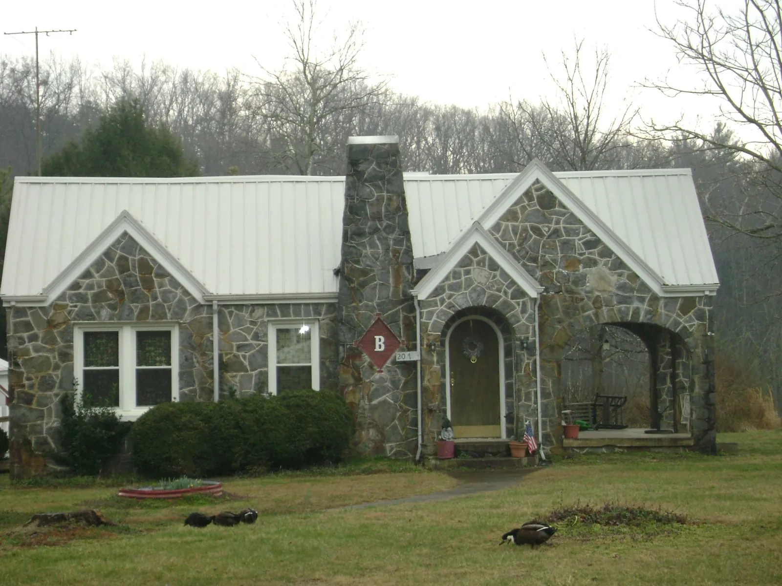 White metal roof on a stone cottage with steep gables in Millville